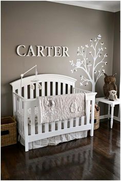 a white nursery crib next to a brown wall with the name carter on it