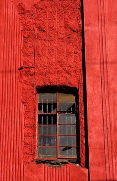 a red building with a window and bars on it