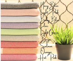 a stack of folded towels next to a potted plant on a table with the names of each towel