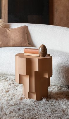 a table that has some books on it in front of a couch with pillows and a pillow