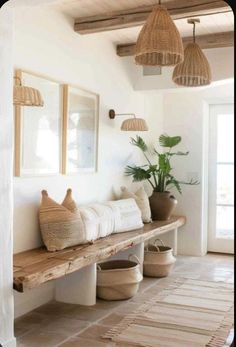 a wooden bench sitting under two hanging lights next to a potted plant and mirror