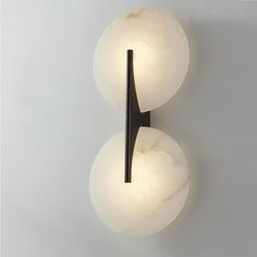 two white balls mounted on a wall with one light turned on and the other turned off