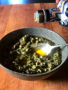 a bowl full of food with a spoon in it and a bottle next to it