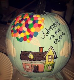 a painted pumpkin with a house and balloons on it