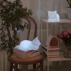 a cat lamp sitting on top of a wooden table next to a potted plant