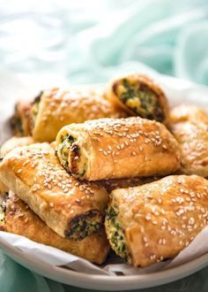 a white plate topped with pastries on top of a blue table cloth covered in sesame seeds