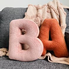 the letter b is made out of foam and sits on a couch next to a throw blanket