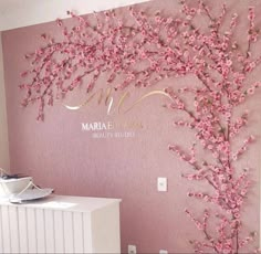 the wall is decorated with pink flowers and gold lettering