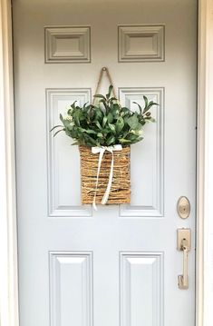 a basket with flowers hanging on the front door