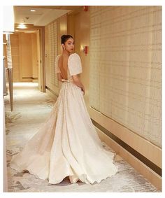 a woman in a wedding dress standing next to a wall