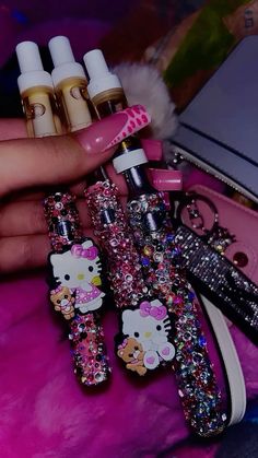 hello kitty nail polish and other items are on a pink surface next to a purse