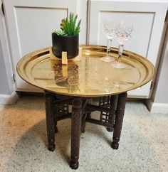 a table with two wine glasses and a plant on it in front of a door