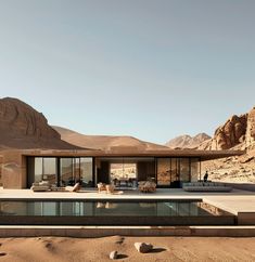 the desert house is surrounded by mountains and sand, with a pool in front of it