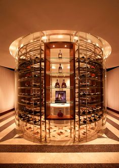 a wine cellar in the middle of a room with shelves full of bottles and glasses