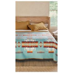 a bed with a blue blanket on top of it next to a wooden headboard