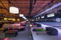 an empty bowling alley with seating and neon lights on the ceiling is seen in this image