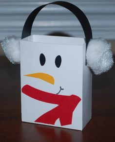 a paper bag with a snowman face on it and pom - poms