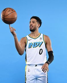 a man holding a basketball in his right hand while standing next to a blue wall