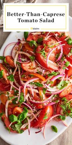 a white plate topped with tomatoes, onions and lettuce next to a fork