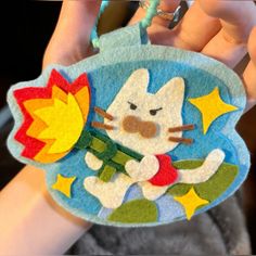 a hand holding a hello kitty ornament with stars and a rocket on it