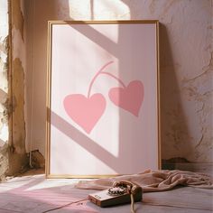 a pink poster with two hearts on it next to a phone and a blanket in front of a window