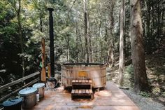 a hot tub sitting on top of a wooden deck in the woods next to trees