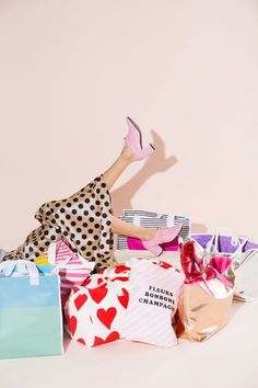 a woman laying on the ground surrounded by bags and shopping bags, with her legs up in the air