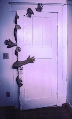 several hands reaching out from behind a door