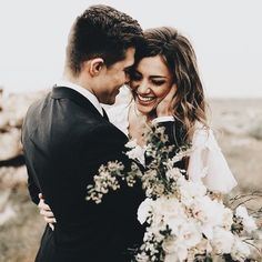 a bride and groom embracing each other in the desert