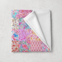 a pink and blue floral print blanket folded on top of a white tablecloth with an open pocket