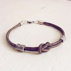 a brown leather bracelet with silver clasps on a white surface, close - up