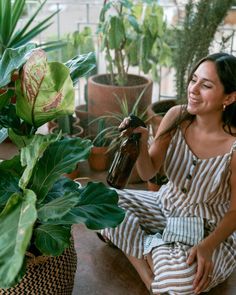 a woman sitting on the ground next to potted plants