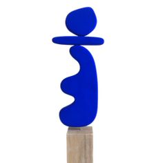 a tall blue sculpture sitting on top of a wooden block in front of a white background