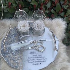 three pieces of jewelry sitting on top of a white furnishing next to flowers