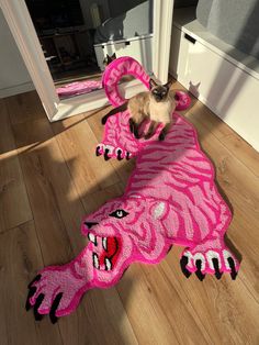 a siamese cat standing on top of a pink rug that looks like a tiger