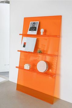 an orange shelf with pictures and other items on it