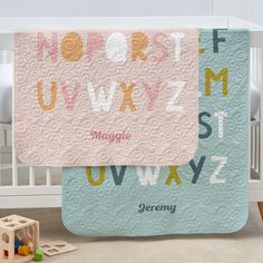 a baby crib with a blanket that has letters and numbers on it