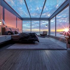 a bedroom with large windows overlooking the ocean at sunset or sunrise, is pictured here