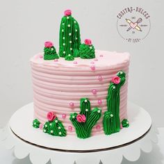 a cake decorated with pink frosting and green cactus decorations