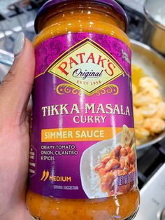 a hand holding a jar of tikka masala curry