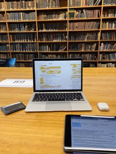 an open laptop computer sitting on top of a wooden table next to a smart phone