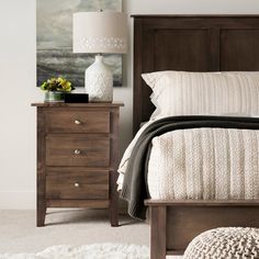 a bedroom scene with focus on the bed, nightstand and night stand in the foreground