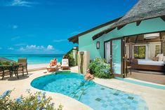 two people are sitting at the edge of a swimming pool in front of an ocean view