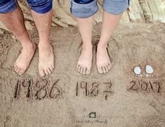 two people standing in the sand with their feet up