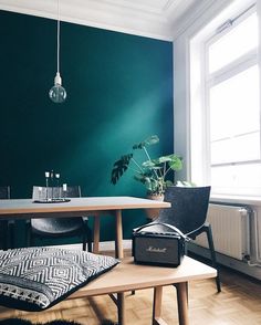 a dining room with green walls and wooden flooring in the center is a table, two chairs, an airplugged potted plant on top