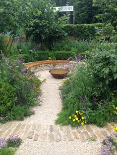 a garden with flowers, rocks and plants around it in the middle of a path