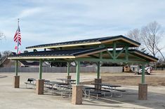 a picnic area with tables and an american flag in the background