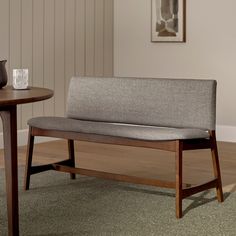 a wooden bench sitting on top of a carpeted floor next to a small table