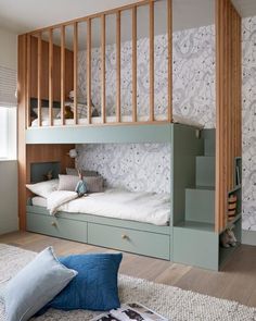 a bedroom with bunk beds and pillows on the floor in front of a wallpapered wall