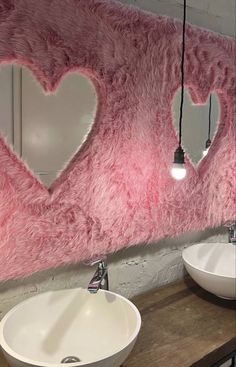 two sinks in front of a pink heart shaped wall